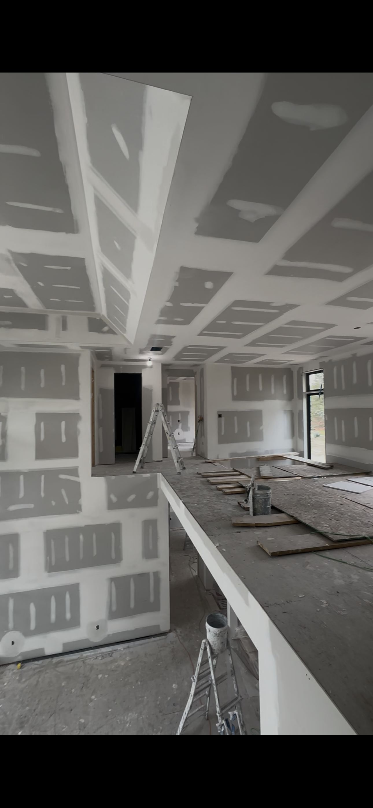 New build drywall — coffered ceiling layout, large open plan, taping in progress