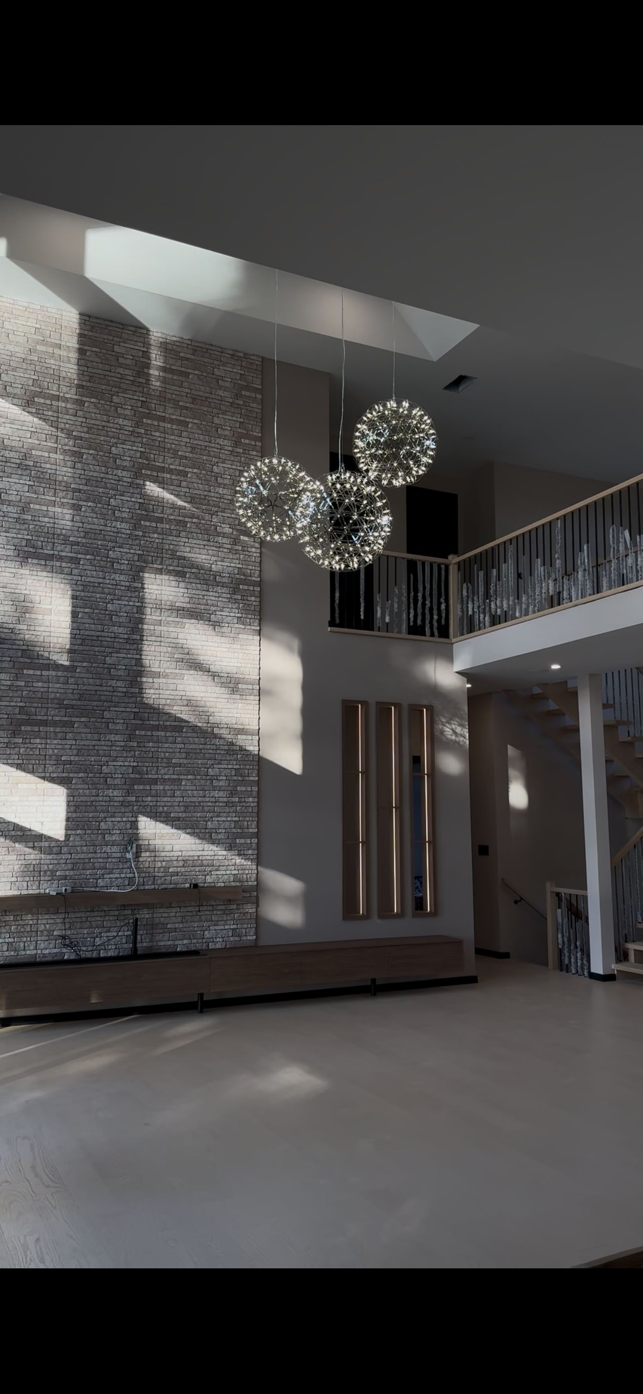 Interior finishing — grand two-storey foyer with stone feature wall and crystal pendants