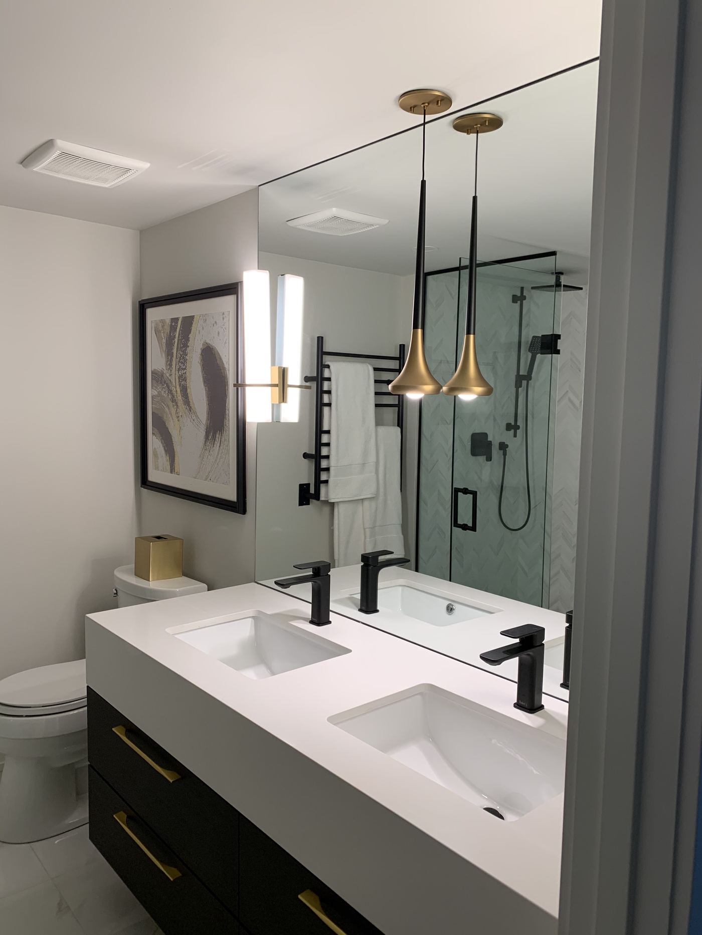 Bathroom renovation — double sink vanity, black and gold fixtures, pendant lighting