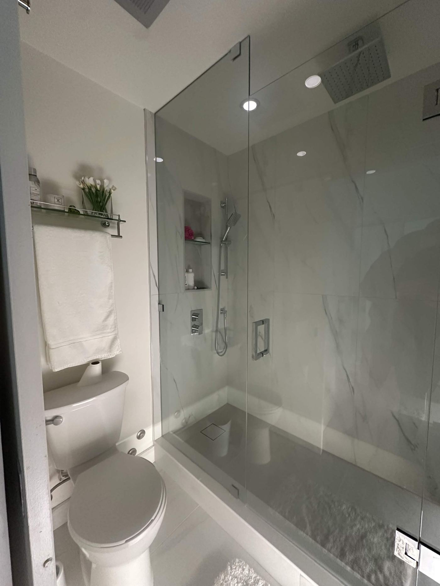 Bathroom renovation — white marble walk-in shower, chrome fixtures, glass enclosure