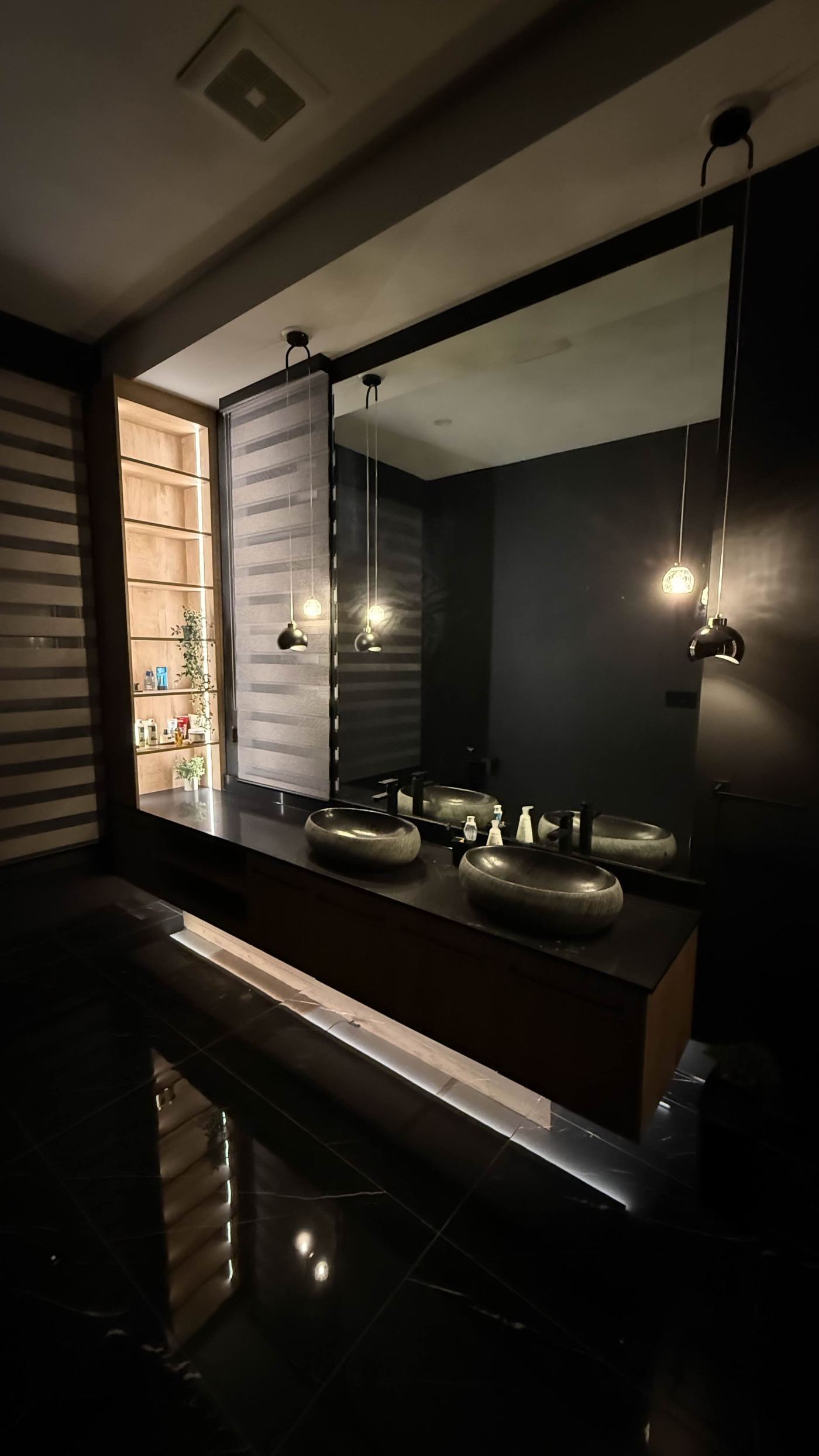 Bathroom renovation — all-black double vanity with stone vessel sinks, pendant lighting