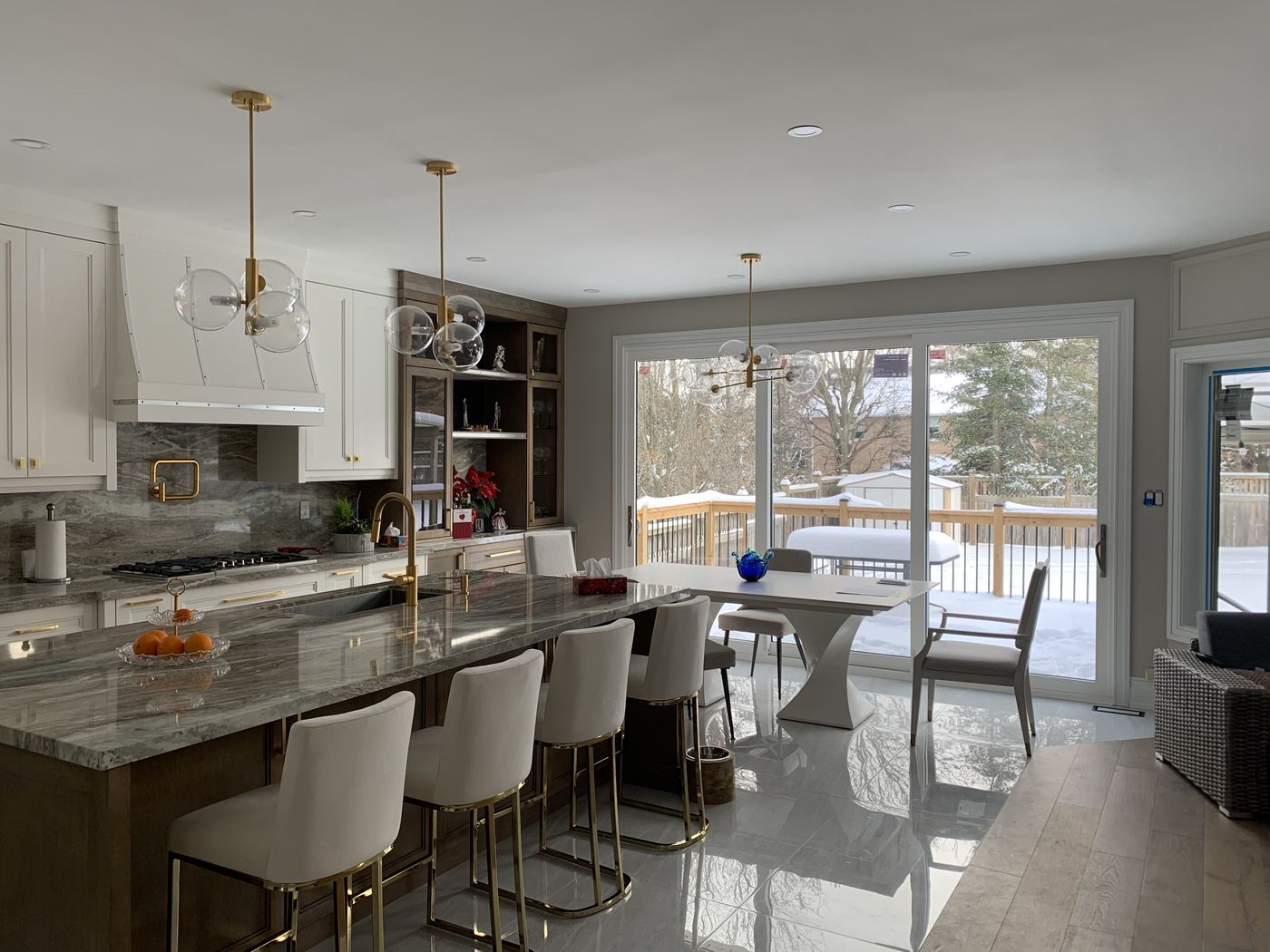 Kitchen renovation — white cabinets, granite island, gold pendants