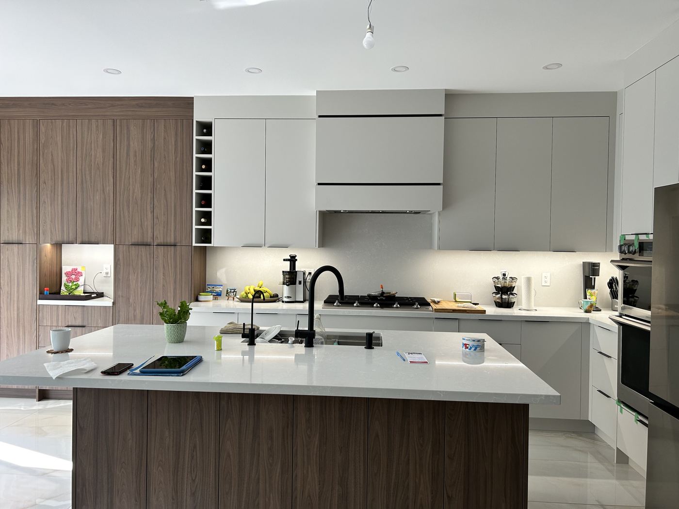 Kitchen renovation — grey and walnut two-tone flat-panel cabinetry, large island, black fixtures
