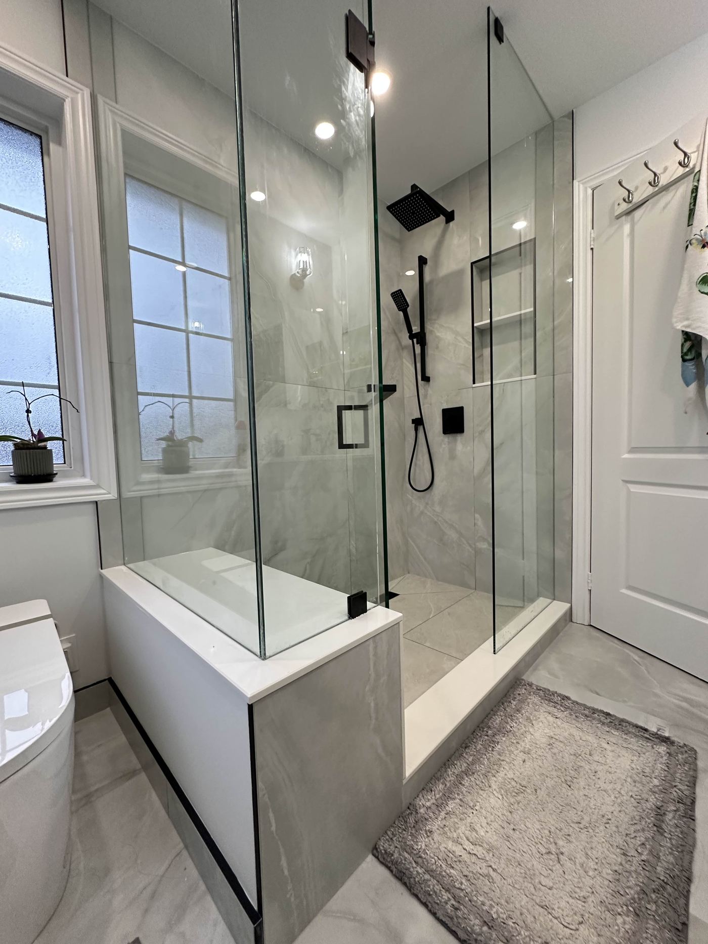 Bathroom renovation — marble walk-in shower, matte black fixtures, glass enclosure