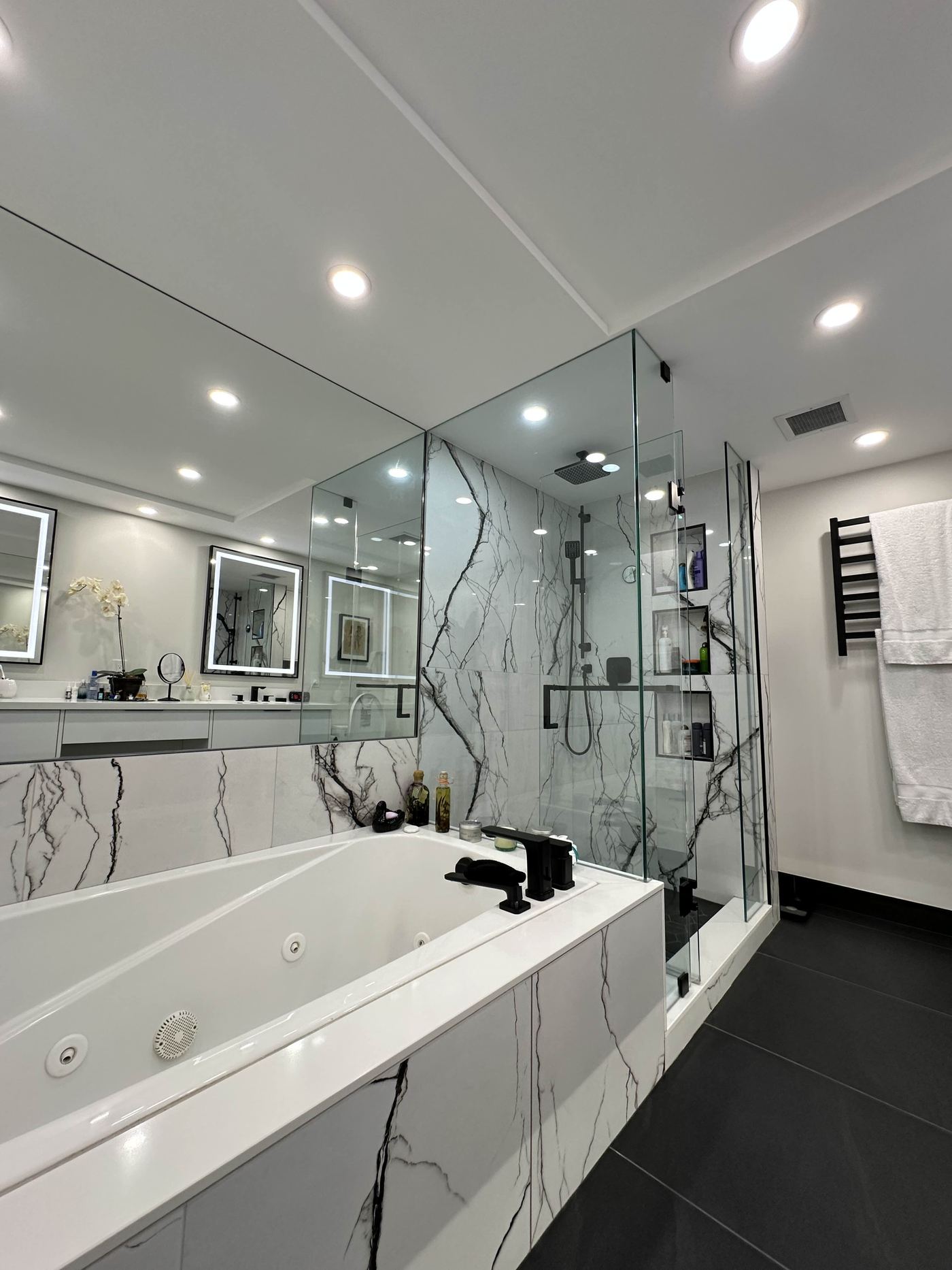 Bathroom renovation — marble soaker tub surround, glass shower, matte black fixtures