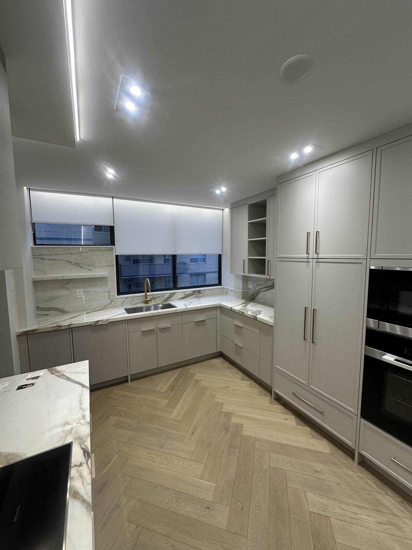 Kitchen renovation — full L-shape view, ribbed grey cabinetry, double wall oven