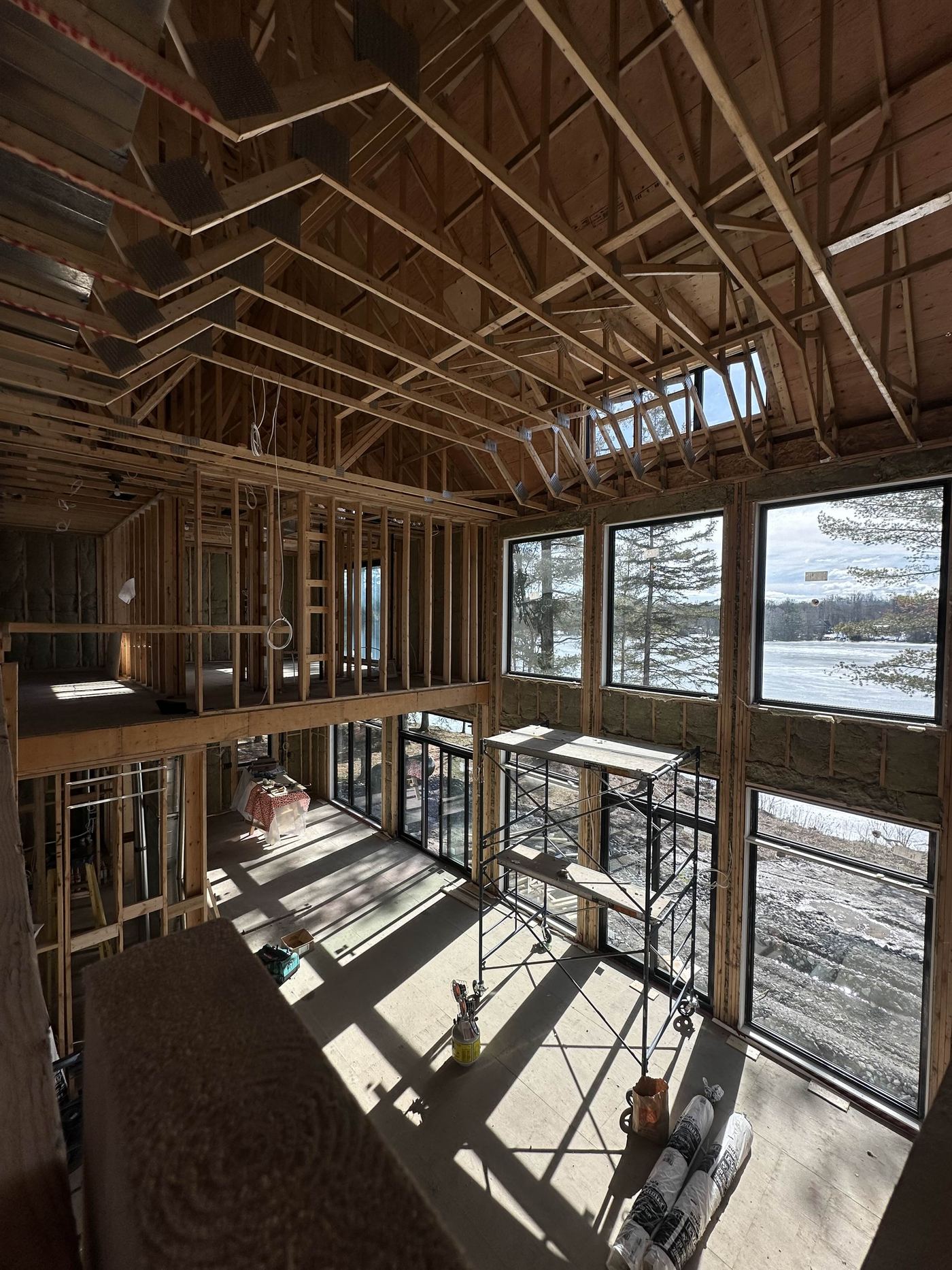 New build framing — two-storey open frame, panoramic windows, lake views